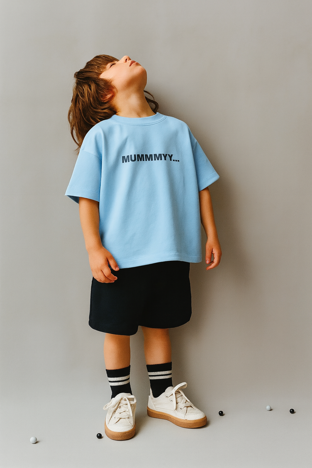 Child wearing a light blue t-shirt with 'MUMMY...' text, standing against a plain background.